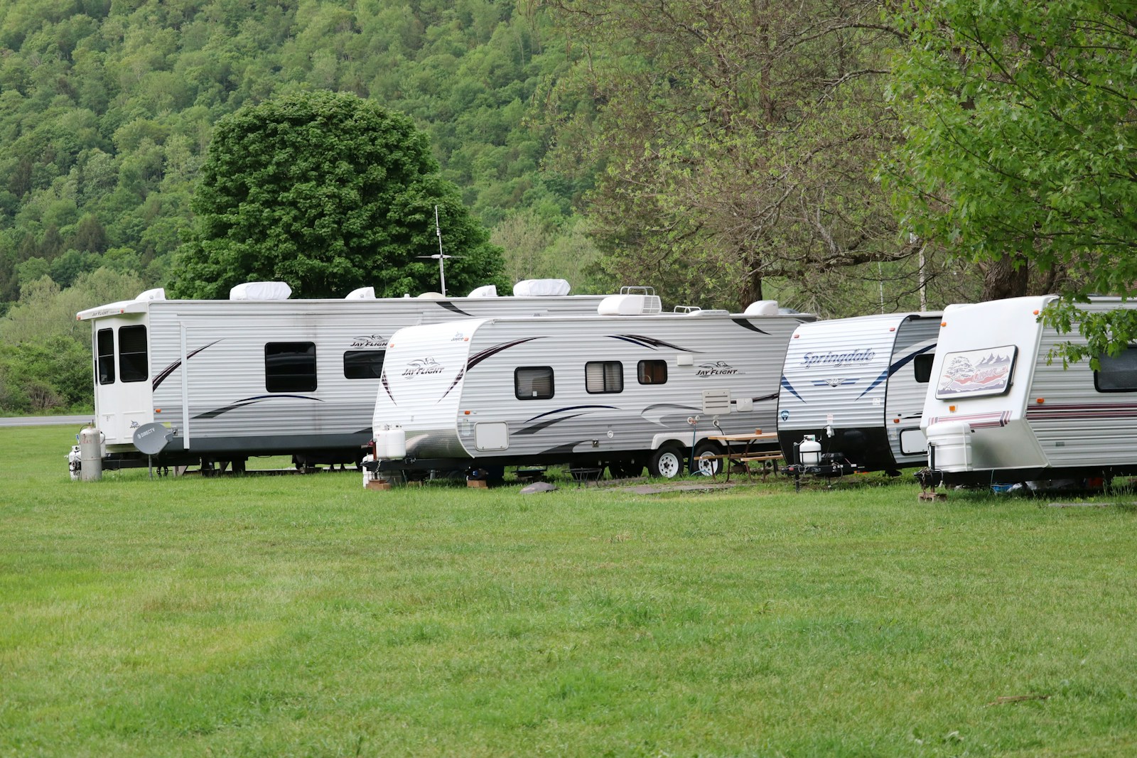 white and brown rv trailer on green grass field during daytime